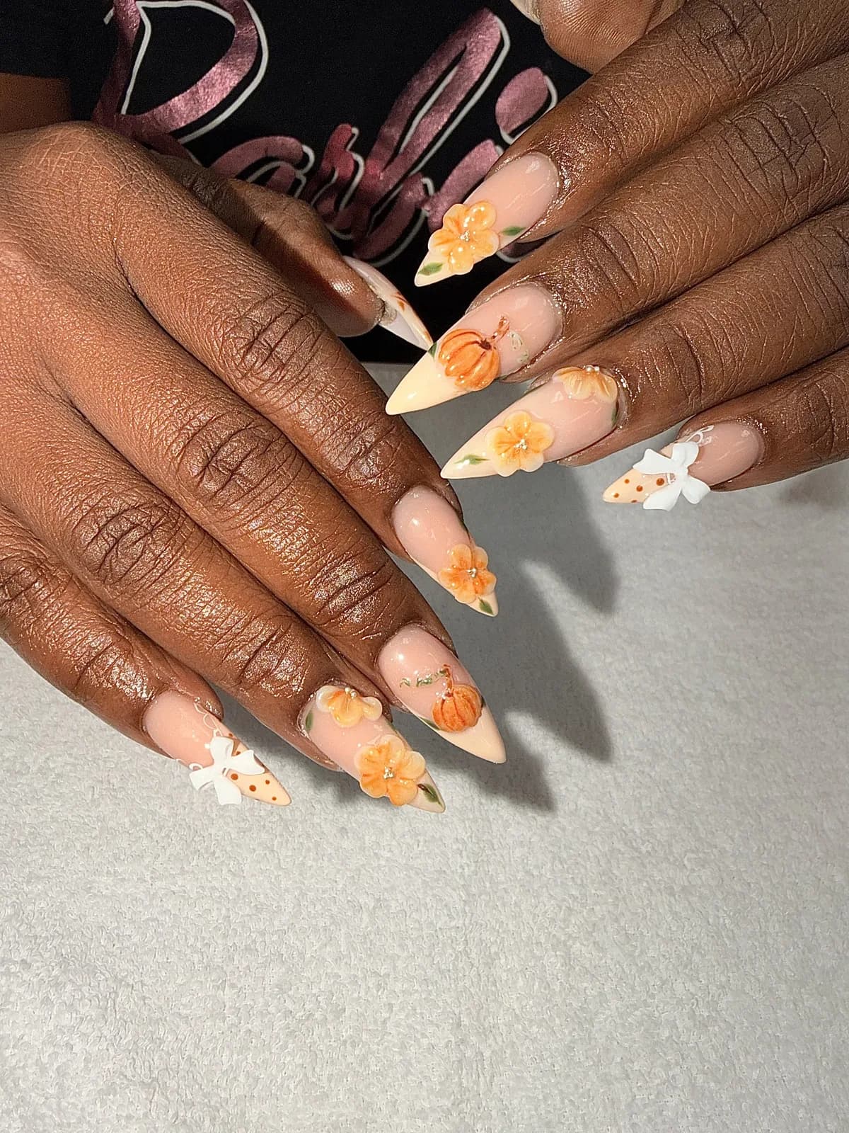Peach stiletto nails with 3D pumpkins and flowers, Halloween and fall nail art at G Salon & Spa in Port St. Lucie, FL
