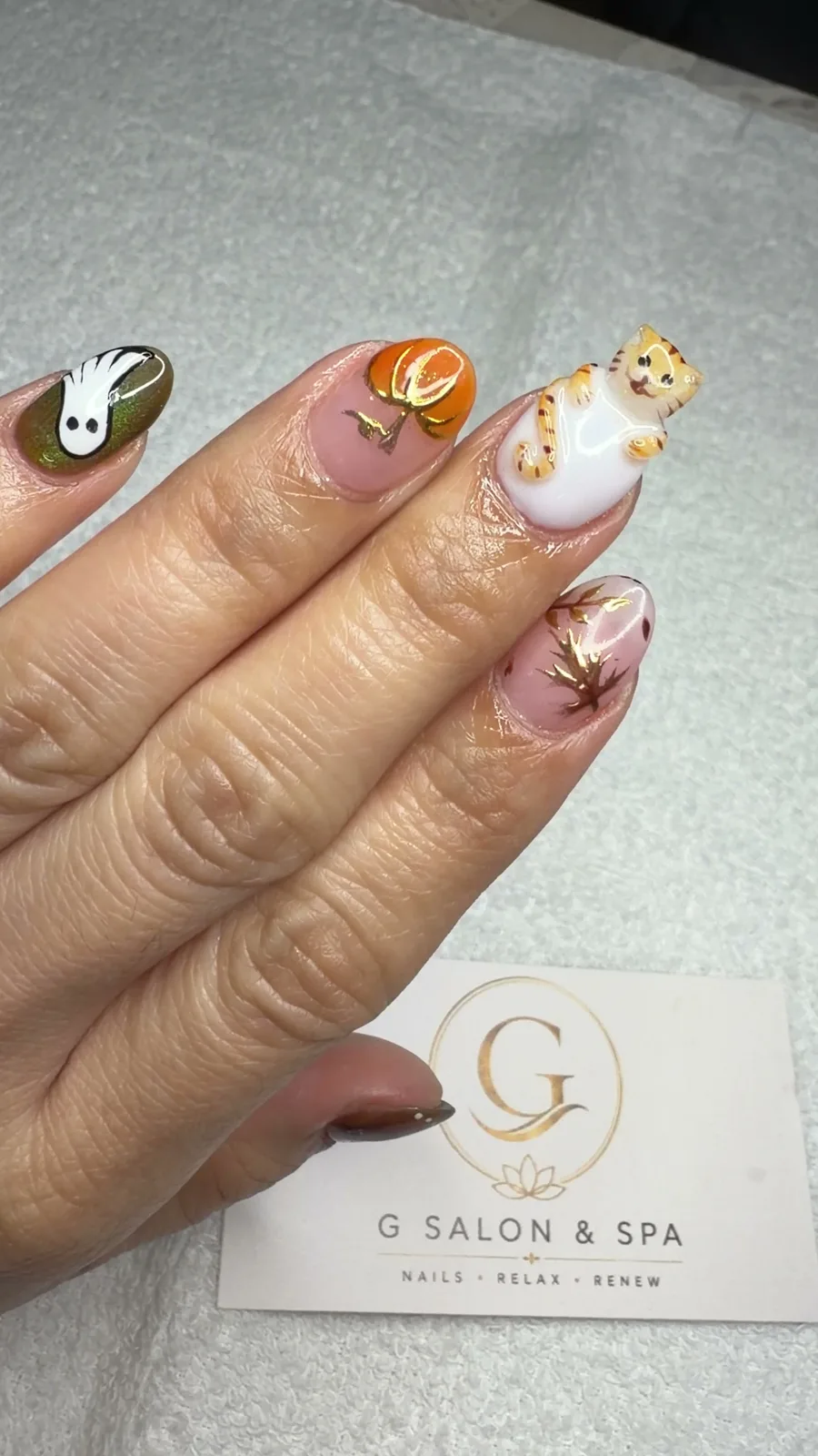 Halloween nail art with a white ghost, an orange pumpkin and a 3D cat on short nails at G Salon & Spa in Port St. Lucie, FL