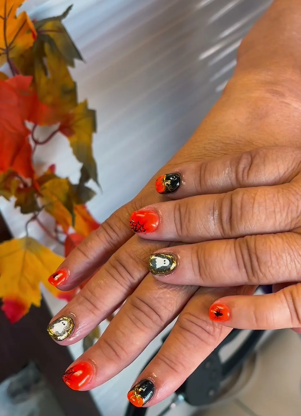 Orange and black Halloween nails with ghost, spiderweb and pumpkin art at G Salon & Spa in Port St. Lucie, FL