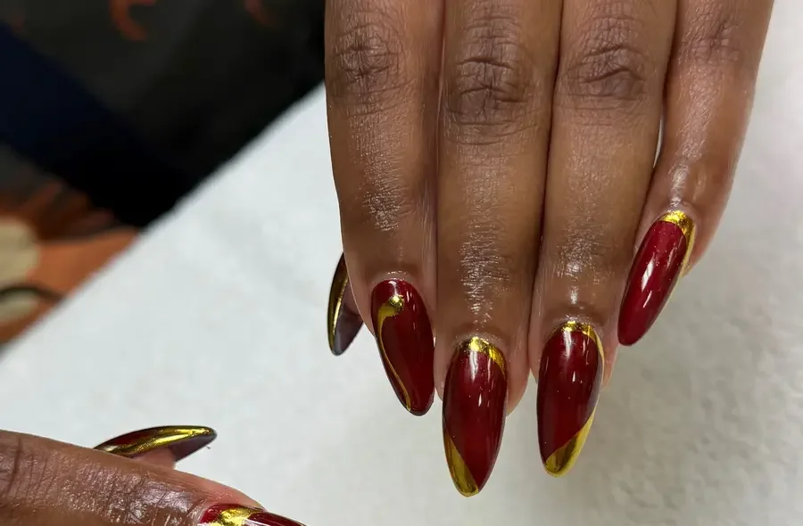 Oxblood red almond nails with mirror-gold chrome French edges, a real set done at G Salon & Spa in Port St. Lucie, FL