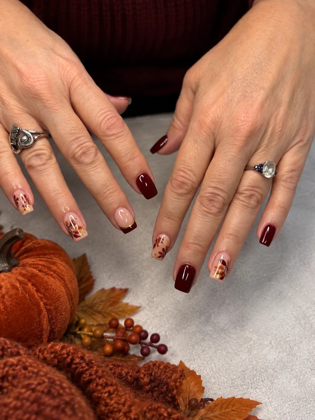 Merlot square nails with hand-painted autumn leaves on nude accent nails at G Salon & Spa in Port St. Lucie, FL