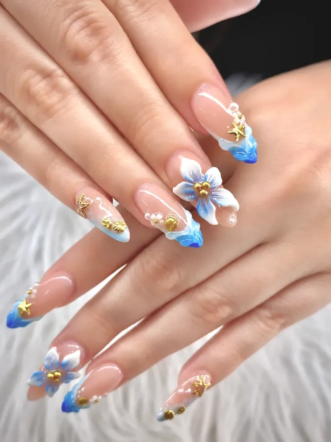 Real nail design done at G Salon & Spa — blue French tips with 3D flowers and crystals