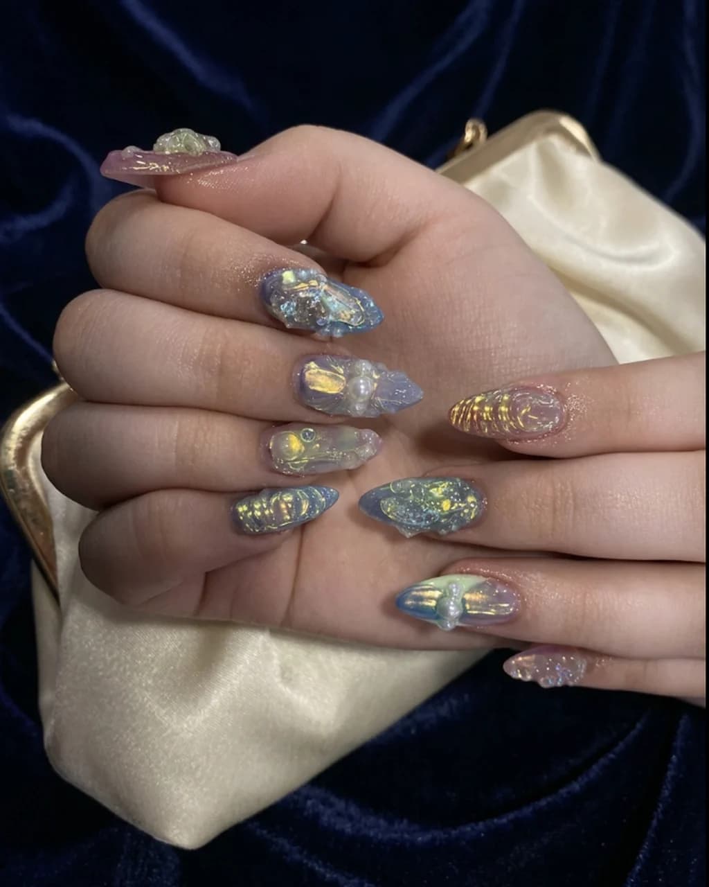 Inspired by a real G Salon set: iridescent aurora chrome almond nails with raised 3D detail on an ivory satin clutch