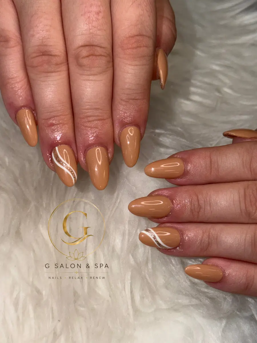 Caramel nude almond nails with a white swirl accent, done at G Salon & Spa