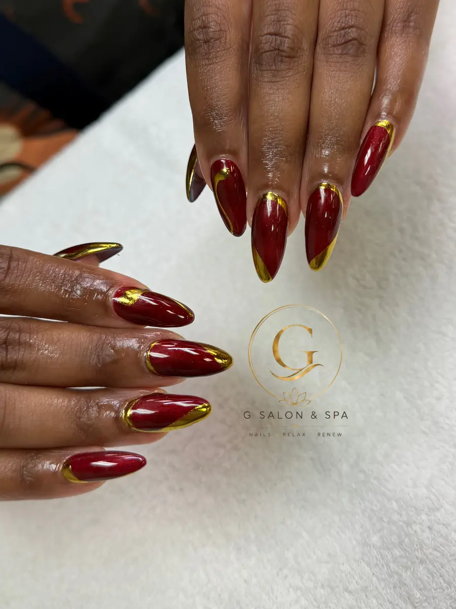 Oxblood red stiletto nails with gold chrome French edges, a real set done at G Salon & Spa in Port St. Lucie, FL