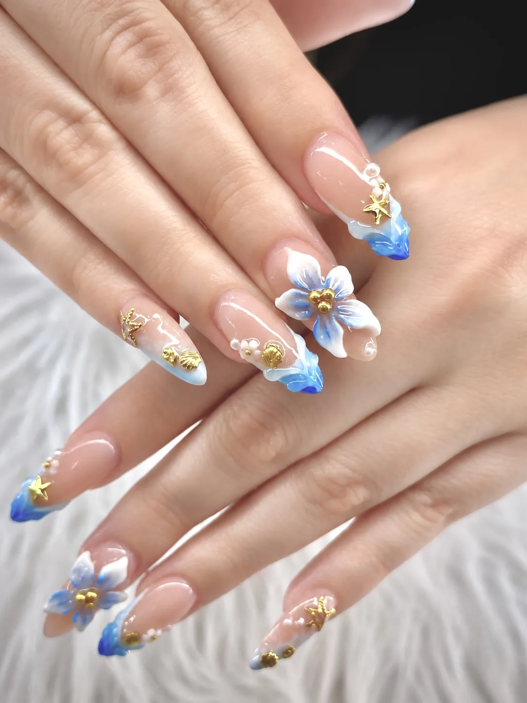 Almond nails with blue 3D flowers, gold starfish charms and blue French tips