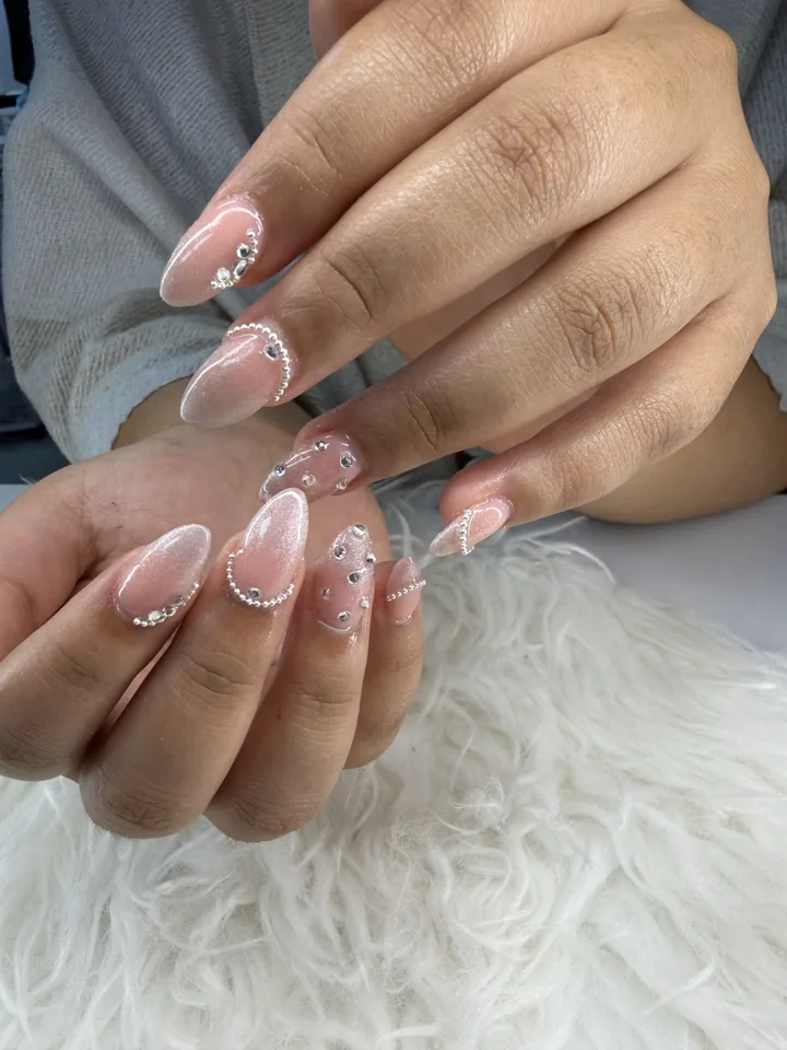 A real G Salon client set: sheer pink almond nails with pearl and rhinestone accents